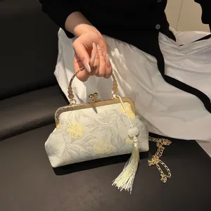 Detail of vintage floral qipao bag with gold frame, metal handle and white silk tassel
