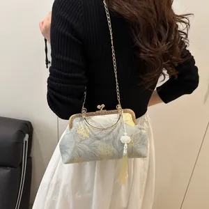 Close-up of retro shell bag with gold floral patterns and white tassel on model
