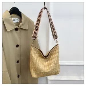 Gros plan d'un sac bandoulière tissé avec une sangle large à motifs géométriques