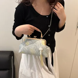 Detail of blue floral qipao shell bag with metal handle and long beige tassel accessory