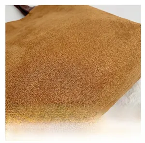 Macro detail of brown frosted suede fabric texture and leather handle on a tote bag