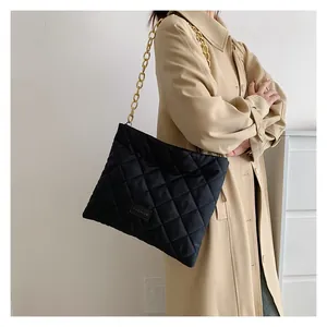 Detail of black quilted shoulder bag with gold chain strap and fashion label on tote