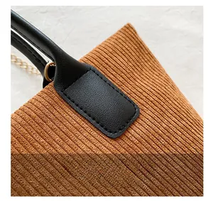 Detail showing high-quality stitching and faux leather handle on brown corduroy tote bag