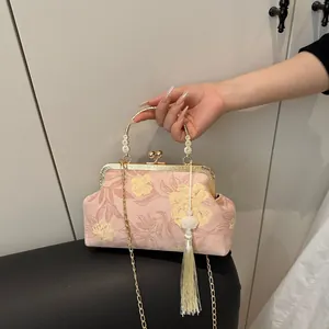 Detail of pink floral brocade handbag with ornate gold handle and white silk tassel