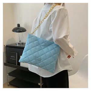 Detail of light blue quilted crossbody bag with chunky gold chain strap and FASHION label