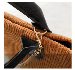 Detail of caramel corduroy fabric with golden metal lobster clasp and black leather handle