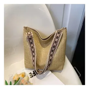 Détail du sac en paille avec bandoulière jacquard géométrique et boucles dorées