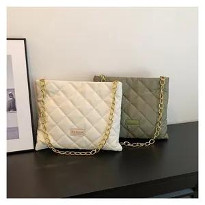 Close-up of quilted fashion handbags with gold chain straps in cream and olive green