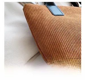 Detail shot of the corduroy fabric texture and premium black leather handles of the tote bag