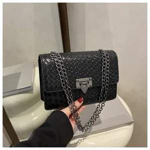 Detail of black woven texture on flap crossbody bag with gunmetal chain strap
