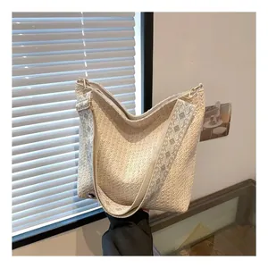 Détail du sac hobo tissé blanc cassé avec une large bandoulière brodée grise