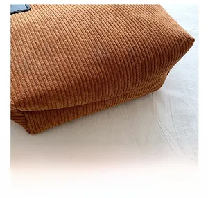 Macro detail of a brown corduroy tote bag showing the reinforced wear-resistant bottom
