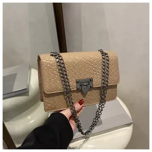 Detailed close-up of apricot woven texture handbag with dark grey metal chain strap