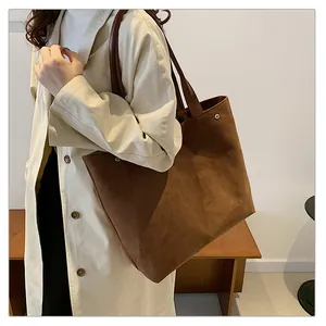 Detailed view of large brown frosted suede tote bag worn with a white coat