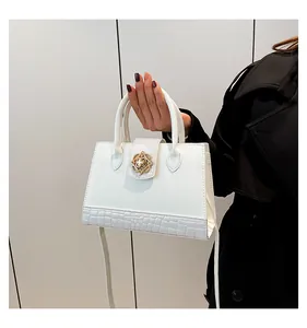 Detail of white leather handbag with croc-embossed texture and gold clover buckle