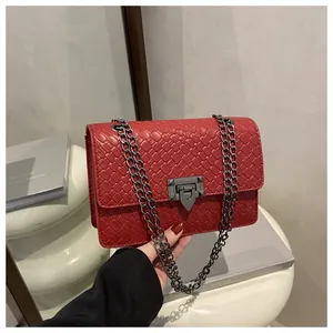 Detail of red faux leather crossbody bag with woven texture and dark metal chain strap