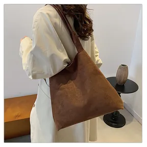 Deep brown oversized suede tote bag shown on model in a minimalist interior setting