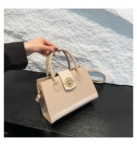 Detail of elegant cream handbag featuring gold floral clasp and crocodile texture accents