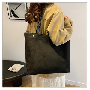 Close-up of black suede tote bag with shiny leather strap and silver metal buckle