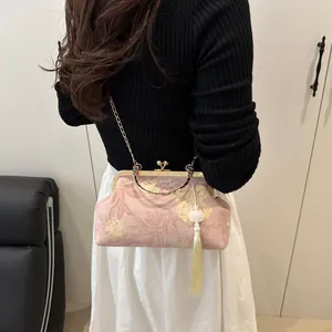 Detail of pink embroidered shell bag with floral patterns, gold frame and long tassel