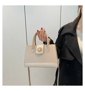 Detail of cream-white handbag featuring crocodile texture and gold flower hardware