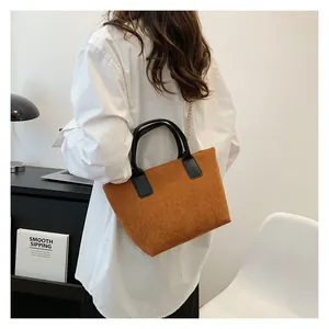 Detail of brown corduroy tote bag featuring black leather handles and gold chain strap