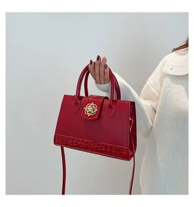 Detail of red croc-embossed leather handbag featuring a decorative gold floral buckle