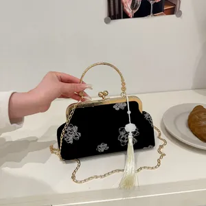 Detail of vintage black velvet handbag with white floral embroidery and silk tassel