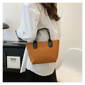 Detail of brown corduroy tote bag with black PU handles and gold metal chain strap