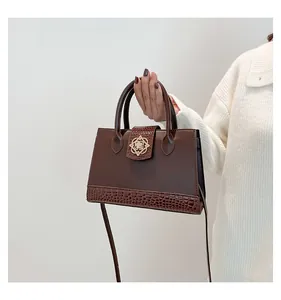 Close-up of vintage dark brown handbag with crocodile embossed texture and golden floral clasp