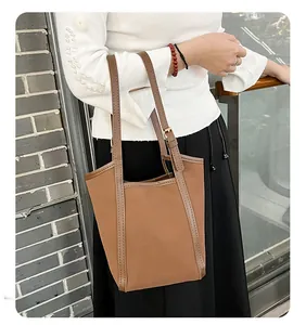 Grand sac cabas marron en nylon avec anses en cuir porté à l'épaule par un mannequin