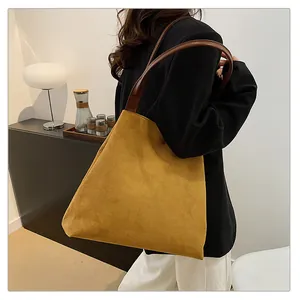 Detail of suede tote bag in ginger yellow with dark brown leather straps on shoulder
