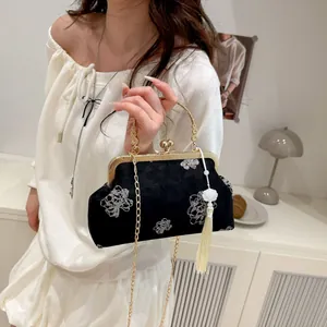 Detail of black velvet qipao bag with silver floral embroidery and golden handle
