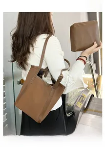 Détail d'un sac seau marron avec pochette assortie tenu par un mannequin en cuir