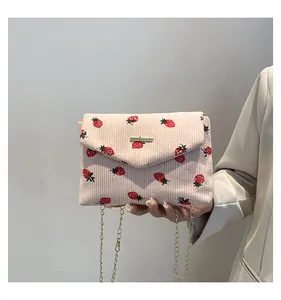 Detail of cream corduroy crossbody bag with strawberry print and gold chain strap