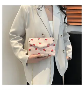 Detail of pink corduroy crossbody bag with strawberry pattern and gold chain strap