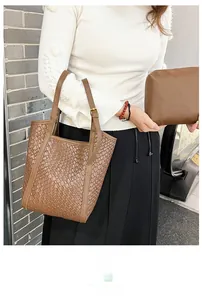 Détail d'un sac cabas marron tissé avec pochette assortie et boucles en métal doré