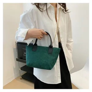 Macro shot of green corduroy tote bag texture with leather handle and gold chain