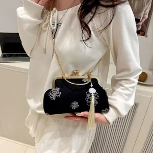Detail of black qipao shell bag with floral embroidery and golden chain strap
