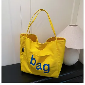 Détail du sac fourre-tout en toile jaune avec imprimé bleu et étiquette noire Fashion