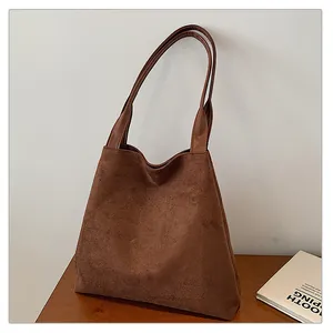 Detail of soft matte suede texture and smooth synthetic leather strap on brown tote bag