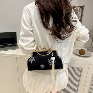 Detail of vintage black velvet shell bag with white floral embroidery and long tassel