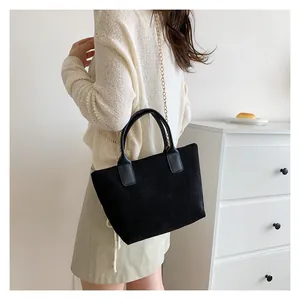 Detail of black corduroy tote bag showing vertical texture and gold chain strap