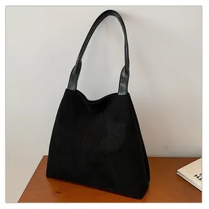 Detail view of the black frosted faux suede texture and leather strap on the tote bag