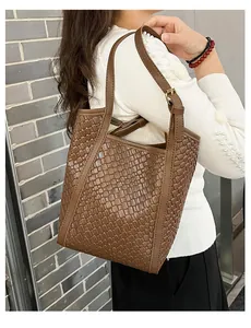 Détail du sac seau marron foncé en cuir tressé avec large bandoulière et boucle en métal