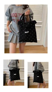 Close-up of black polka dot tote bag with ruffle trim and fashion label detail