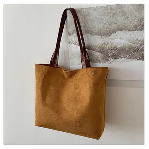 Close-up of matte suede tote bag texture with brown leather strap and silver rivets