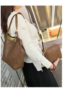 Gros plan sur un sac cabas tressé marron foncé avec petite pochette zippée assortie sur l'épaule
