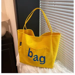 Détail du sac fourre-tout en toile jaune avec imprimé bleu et étiquette de mode