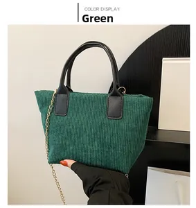 Detailed macro view of dark green corduroy tote bag with black PU handle and gold chain